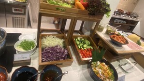 A buffet with various food items including salads, vegetables, and a bowl of beef noodle soup. - Cozy An Boutique Hotel Hoian (Da Nang)