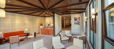 A lobby with a wooden ceiling, a reception desk, and seating areas.