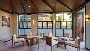 A spacious lounge area with multiple seating options, large windows, and a wooden ceiling. - Cozy An Boutique Hotel Hoian (Da Nang)