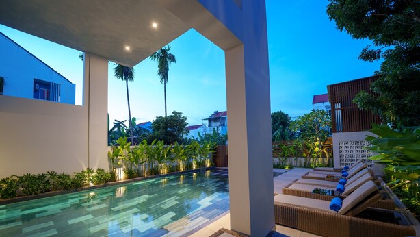 A modern outdoor pool area with lounge chairs and a clear pool. - Cozy An Boutique Hotel Hoian (Da Nang)