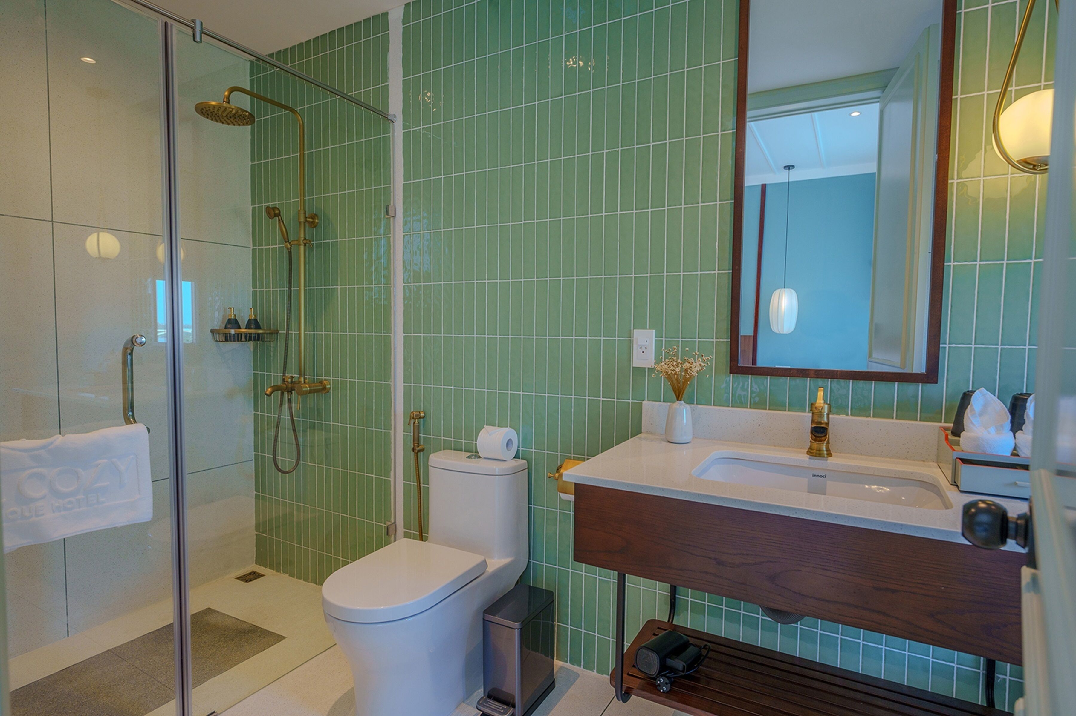 A bathroom with a glass-enclosed shower, a toilet, and a sink with a wooden vanity.