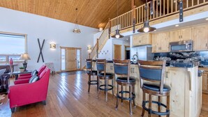 A spacious kitchen with wooden cabinets, a bar area, and a red sofa. - Spacious 5BR Mountain Retreat near Grand Targhee (Driggs)
