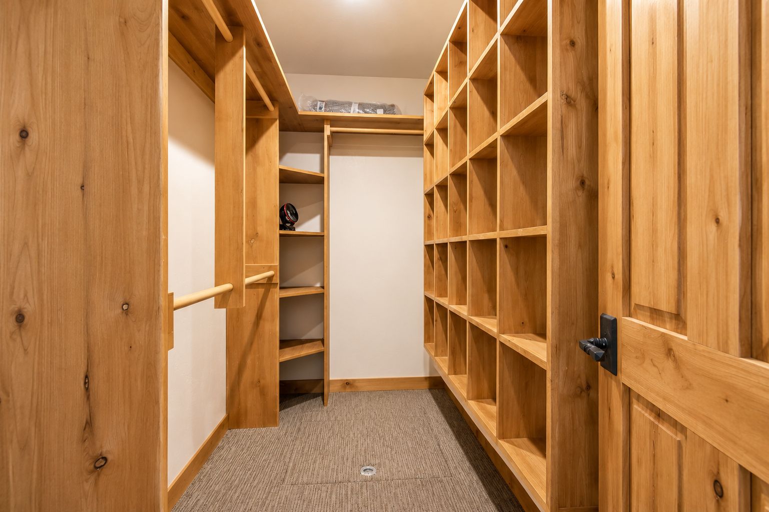 A walk-in closet with wooden shelving and a carpeted floor.