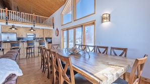 A spacious dining area with a large wooden table and chairs, a kitchen with wooden cabinets and a lofted seating area. - Spacious 5BR Mountain Retreat near Grand Targhee (Driggs)