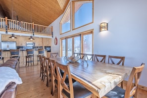 A spacious dining area with a large wooden table and chairs, a kitchen with wooden cabinets and a lofted seating area. - Spacious 5BR Mountain Retreat near Grand Targhee (Driggs)