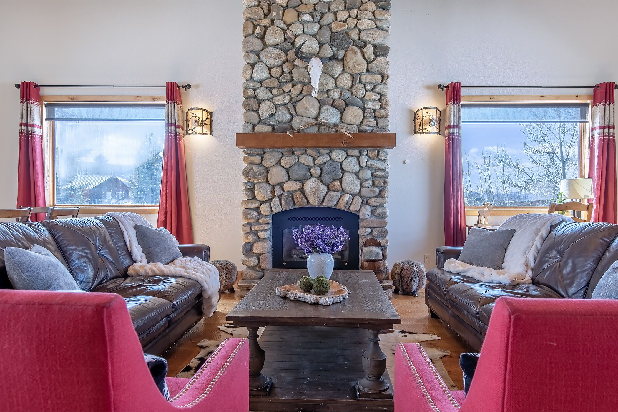 A cozy living room with a stone fireplace, leather sofas, and a wooden coffee table.