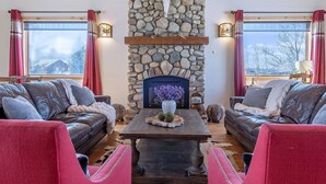 A cozy living room with a stone fireplace, leather sofas, and a wooden coffee table. - Spacious 5BR Mountain Retreat near Grand Targhee (Driggs)