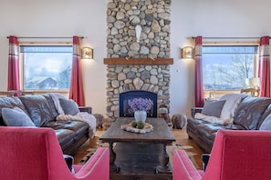 A cozy living room with a stone fireplace, leather sofas, and a wooden coffee table. - Spacious 5BR Mountain Retreat near Grand Targhee (Driggs)