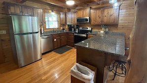 A kitchen with wooden cabinets, stainless steel appliances, granite countertops, and a wooden ceiling. - Alpine Adventure - Mountian home close to attractions! (Pigeon Forge)