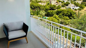 A balcony with a chair, offering a view of a hillside with houses and greenery. - ALTHAIA HILLS- Beautiful townhouse with panoramic terrace and sea and mountain views (Altea)