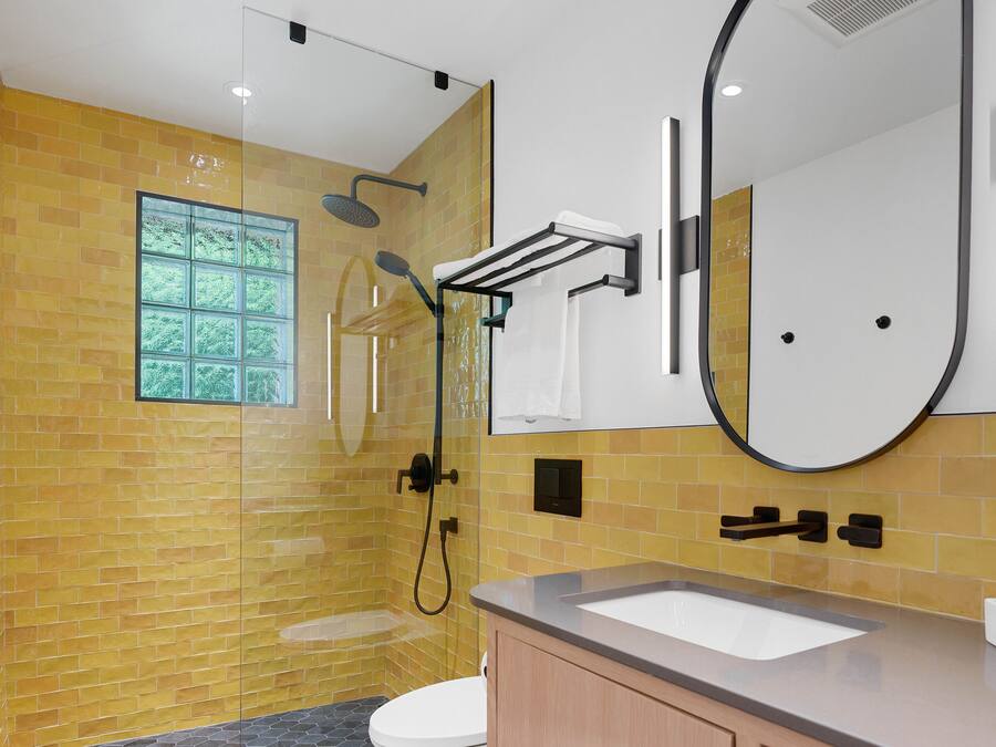 Un baño moderno con ducha envuelta en vidrio, un espejo grande y un lavabo con tocador.