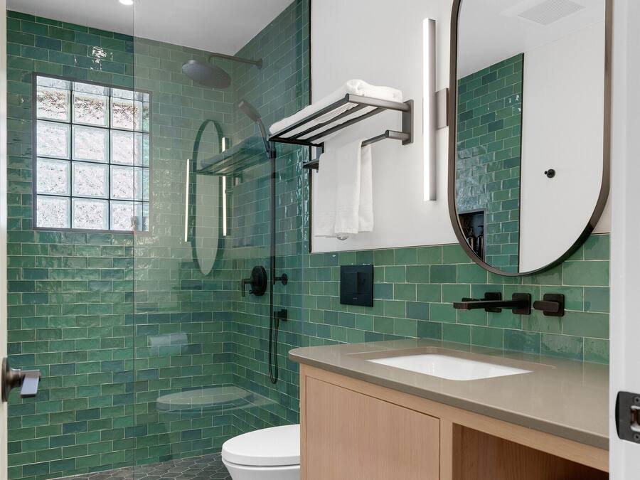 A modern bathroom with a glass-enclosed shower, a white toilet, and a vanity with a mirror.