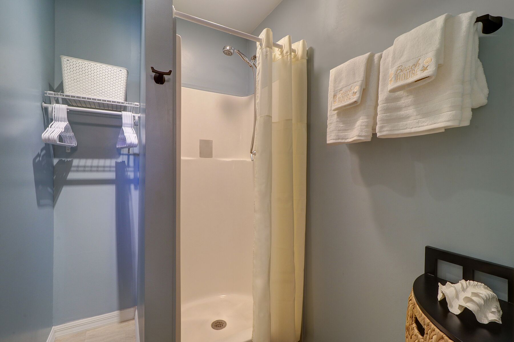 Un baño con ducha, un perchero con toallas y una pequeña mesa con pañuelos.