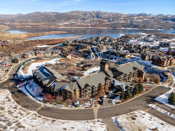 An aerial view of a residential area with houses, roads, and a lake in the background.