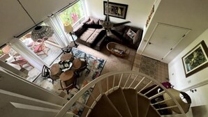 Un'ampia zona giorno con divano, tavolo da pranzo con sedie e una scala che conduce al piano superiore.