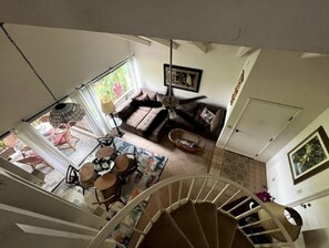 Amplia sala de estar con sofá, mesa de comedor con sillas y una escalera que lleva a un piso superior.