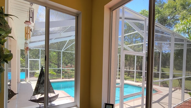 Une chambre avec vue sur une piscine, grâce à une grande fenêtre.