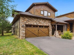 A two-story house with a stone facade, a large garage, and a well-maintained lawn. - Cozy Condo Mountain Views!  So much close by-walk, bike, or drive!  ENJOY! #6182 (Estes Park)