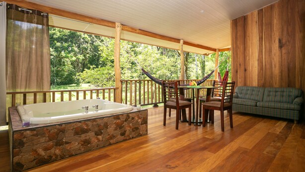 Une terrasse en bois avec une baignoire en pierre, des chaises en bois et un canapé.