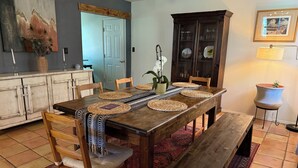 A dining area with a wooden table, woven placemats, and a bench. - Casa del Sol (Taos)