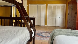 A bedroom with bunk beds, a wooden staircase, a patterned rug, and a wardrobe. - Casa del Sol (Taos)