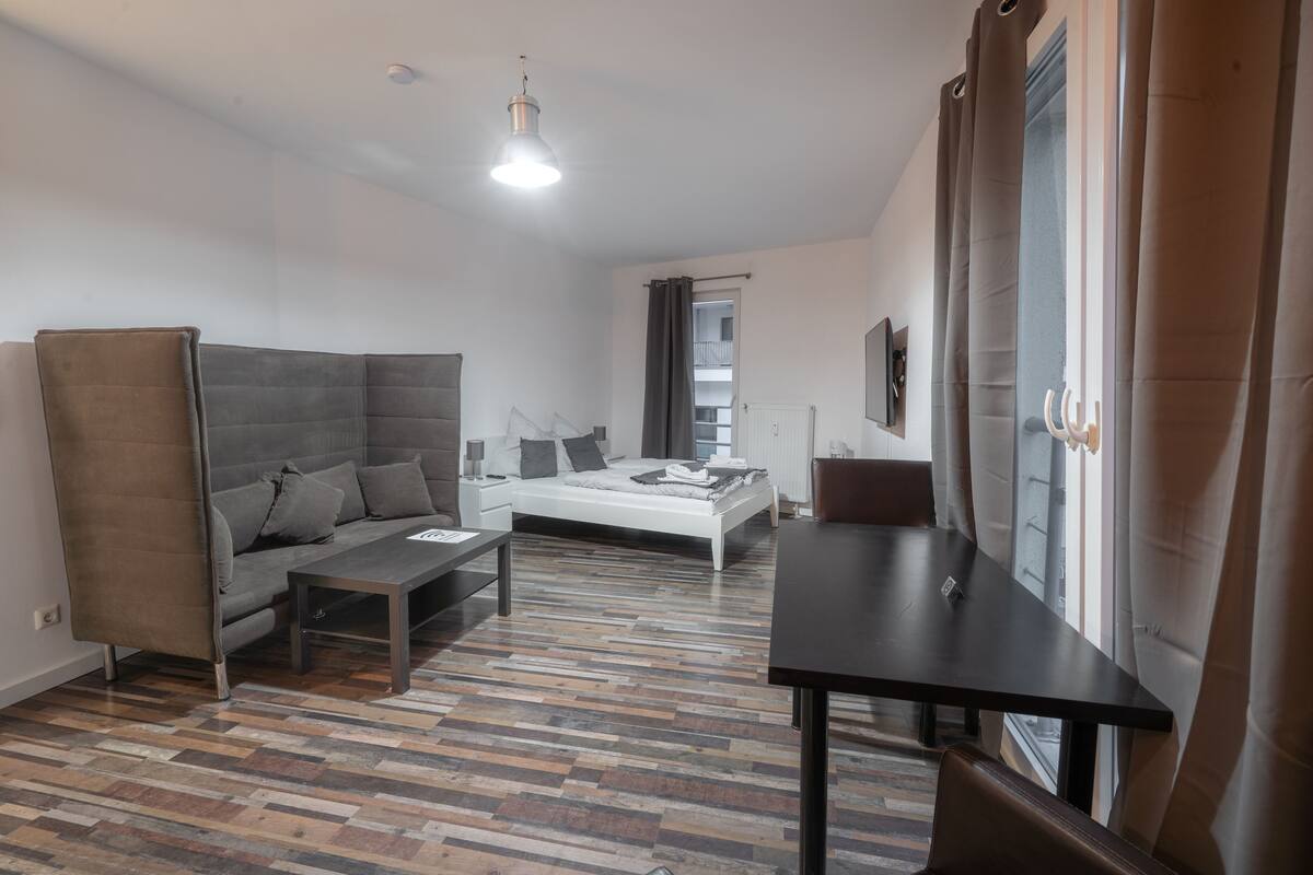 Ein modernes Wohnzimmer mit Sofa, Couchtisch, Bett und Esstisch.