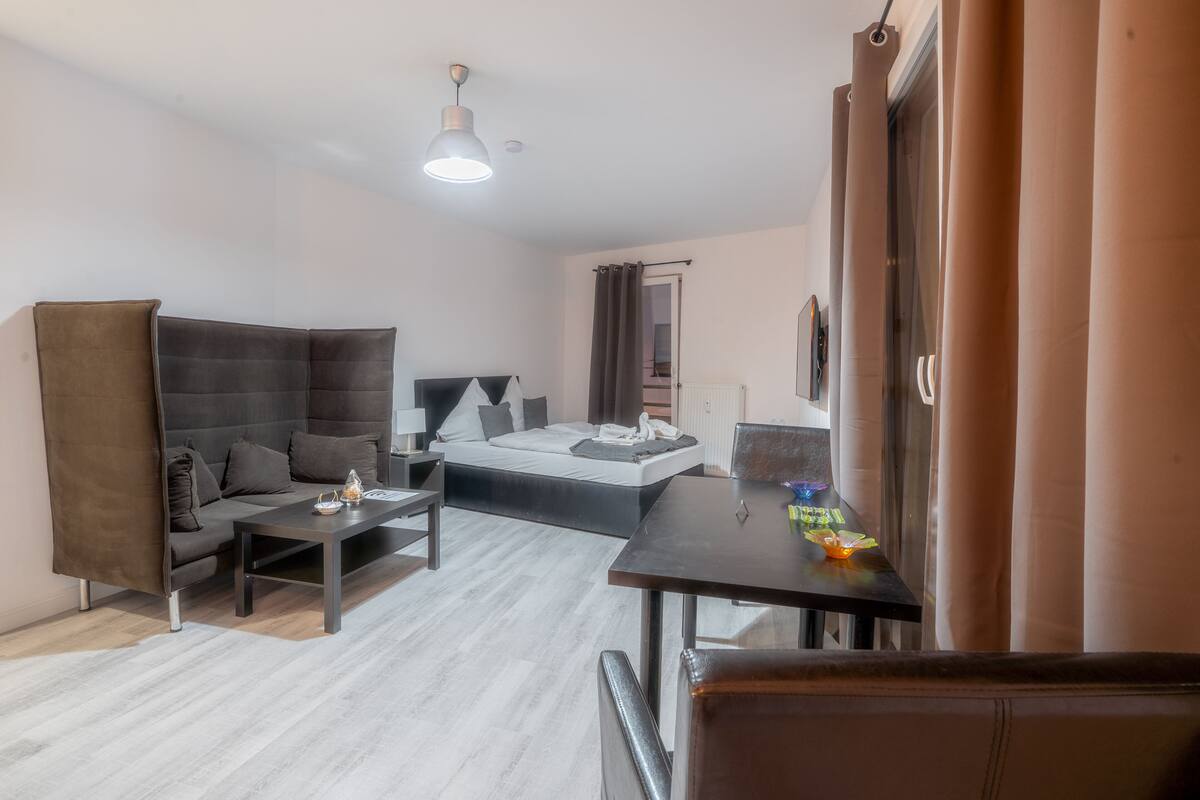Ein modernes Hotelzimmer mit einer Couch, einem Bett, einem kleinen Tisch und einem Schreibtisch.