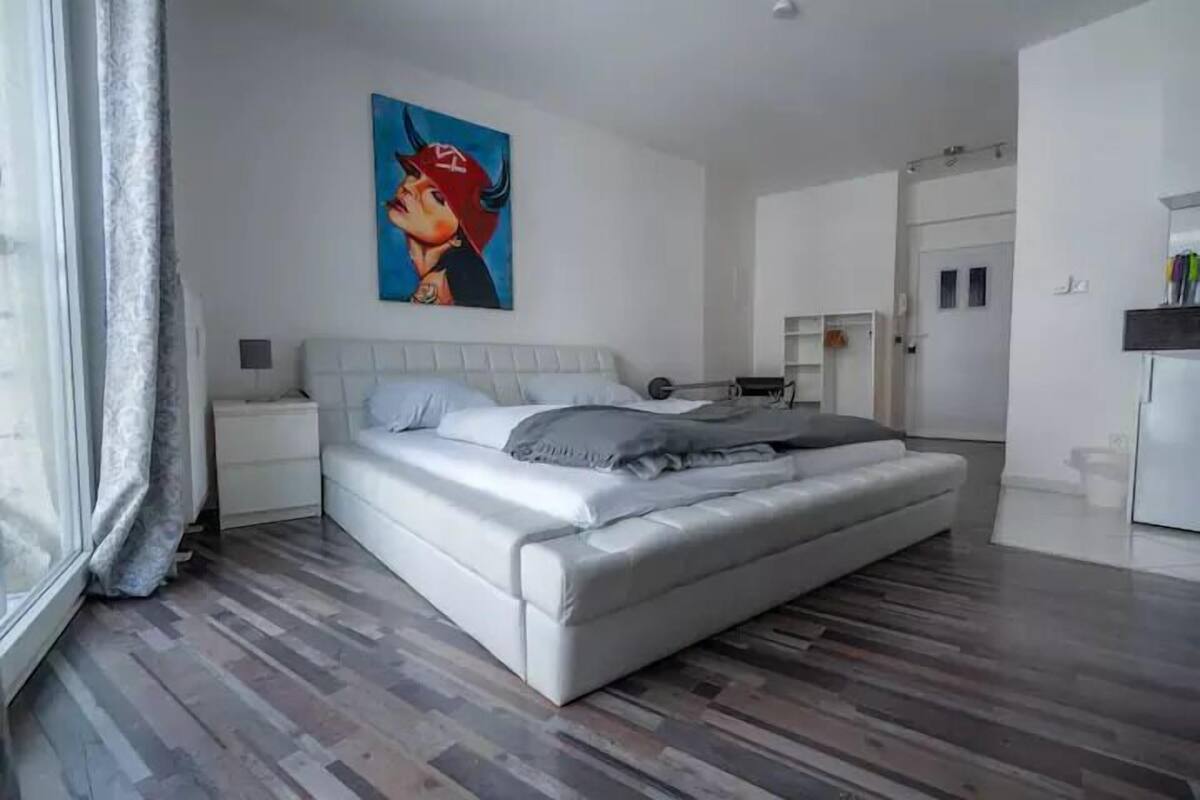 Ein modernes Schlafzimmer mit einem großen Bett, einem Bild an der Wand und Holzboden.