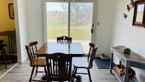 Un comedor con una mesa y sillas de madera, un banco y una pequeña mesa con una planta.