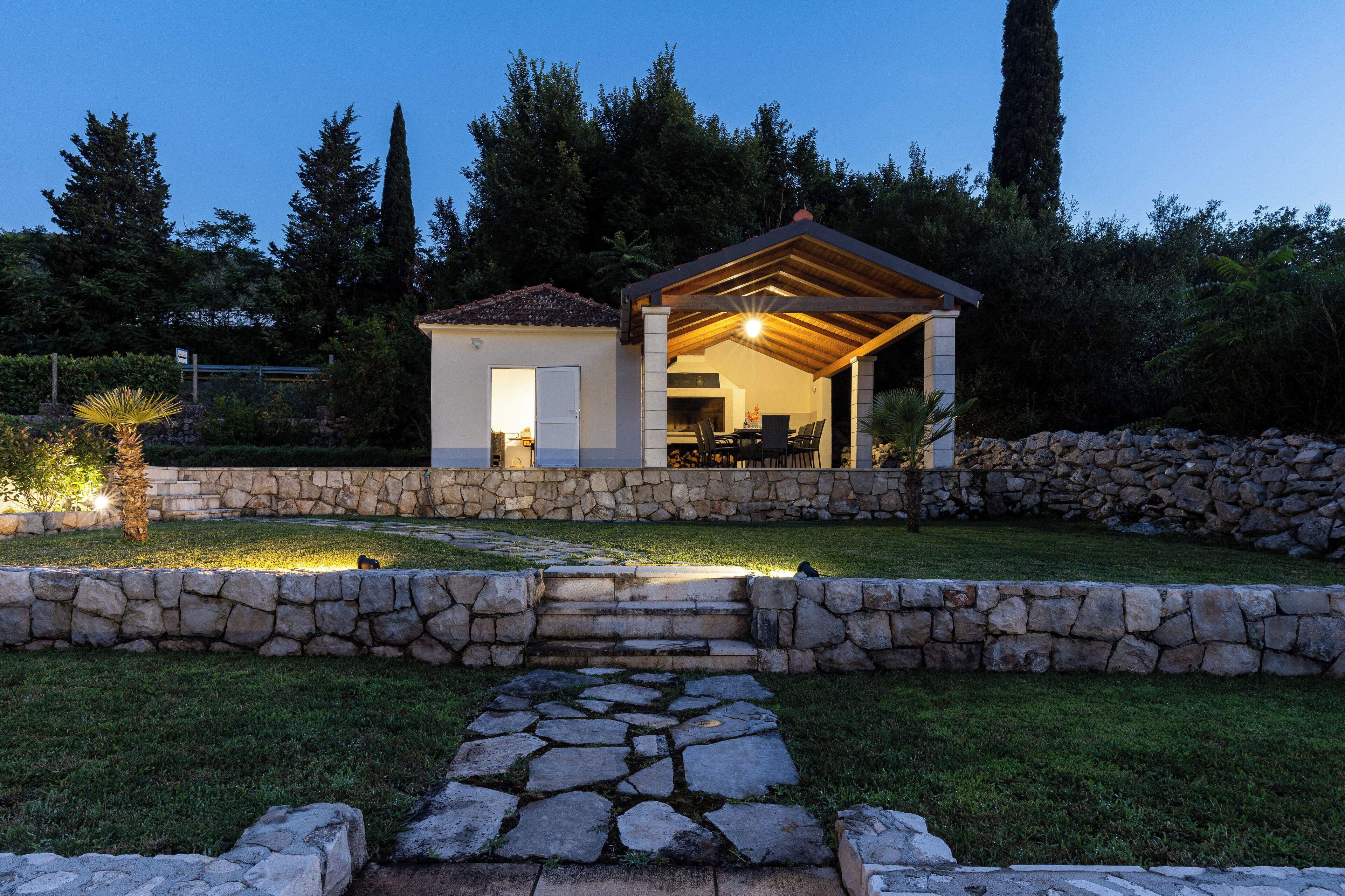 A stone-walled house with a patio and a covered outdoor area.