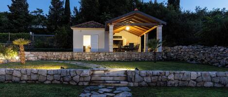 A stone-walled house with a patio and a covered outdoor area.