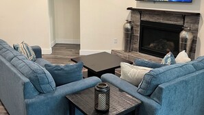 Ein Wohnzimmer mit Ecksofa, Kamin, Flachbildfernseher und Deckenventilator.
