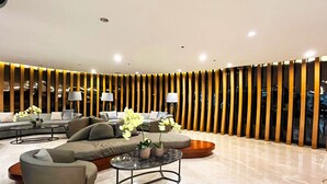 A modern lobby with a sofa set, a coffee table, and a decorative wall with vertical panels. - Shore 2 Residences (Pasay)