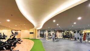 A modern gym with various exercise equipment, a locker area, and a green carpeted section. - Shore 2 Residences (Pasay)