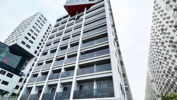 Un moderno edificio de gran altura con varios balcones y una sección superior roja característica.