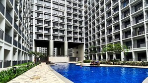 A high-rise building with a central courtyard pool, surrounded by balconies and greenery. - Shore 2 Residences (Pasay)