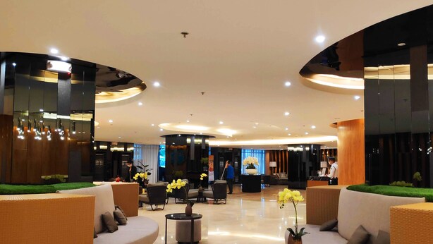 A modern lobby with a curved ceiling, seating areas, and a reception desk. - Shore 2 Residences (Pasay)