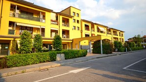 Ein gelbes Mehrfamilienhaus mit Balkonen, einem überdachten Eingang und blauem Himmel.