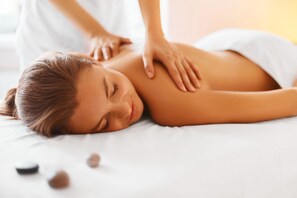 A person receiving a back massage on a bed with a white sheet. - WYLD Glass Caves Durango (Durango)