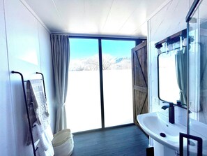 A bathroom with a large window, a sink, and a towel rack.