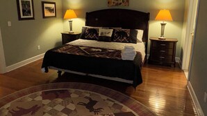 A bedroom with a large bed, two bedside lamps, a rug with animal patterns, and a door to the right. - Hunter Mountain 2 Bedroom Condo - Steps to Ski Slopes!! (Hunter)