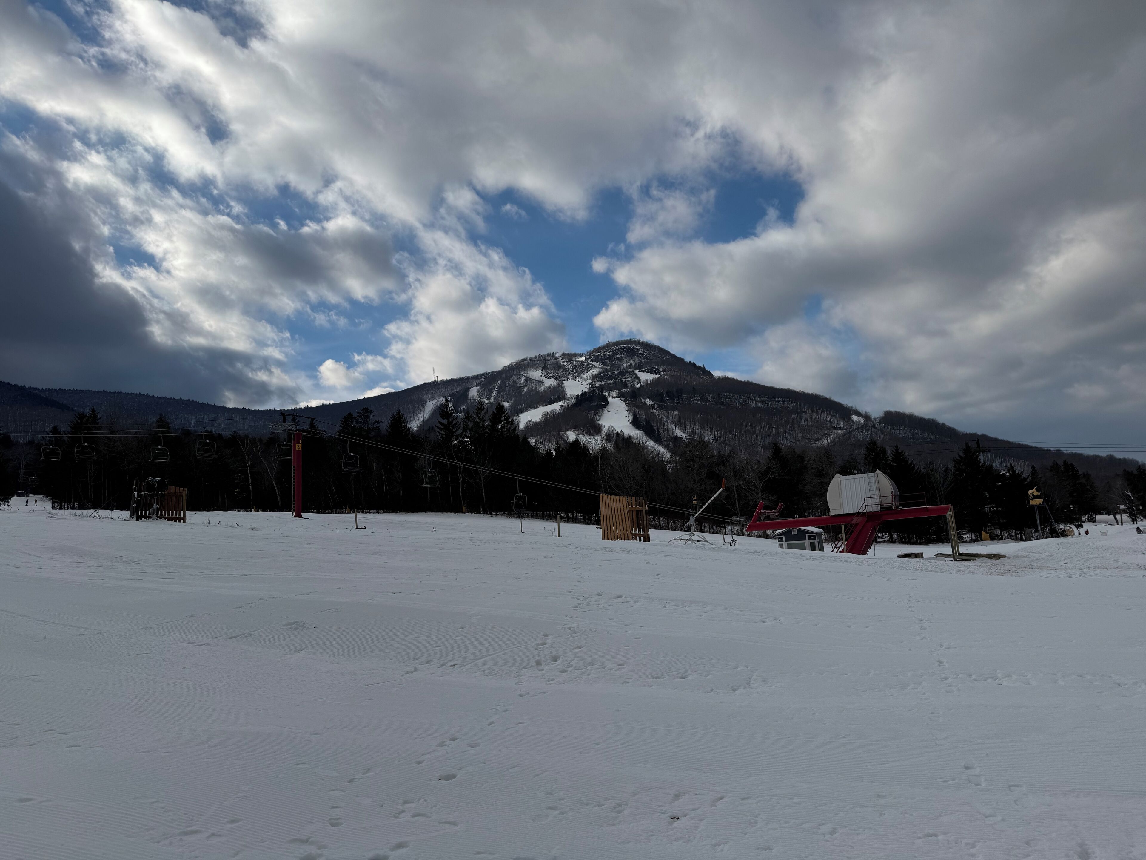Paisaje nevado de montaña con teleféricos y un pequeño edificio.