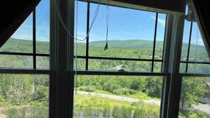 A room with large windows overlooking a natural landscape with a body of water and greenery. - Hunter Mountain 2 Bedroom Condo - Steps to Ski Slopes!! (Hunter)
