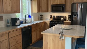 A modern kitchen with wooden cabinets, a stainless steel refrigerator, a microwave, and a gas stove.