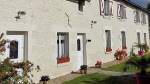 A two-story building with a stone facade, multiple windows with shutters, and a small garden area with potted plants. - La Planchette - SAINT-GERVAIS-LES-3-CLOCHERS (SAINT-GERVAIS-LES-3-CLOCHERS)