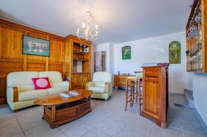 A living room with a wooden cabinet, a chandelier, a television, a sofa, and a coffee table.