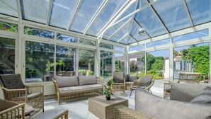 A conservatory with wicker furniture, a sofa, and a potted plant. - La Ribambelle - Saint Hilaire Sous Romilly (SAINT HILAIRE SOUS ROMILLY)
