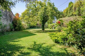 A well-maintained garden with a lawn, a tree, and various shrubs.