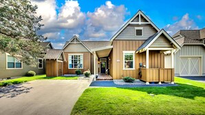 A two-story house with a covered front porch, a garage, and a well-maintained lawn. - Eagle Crest Retreat, HOT TUB, Dogs OK, EV Charger (Redmond)