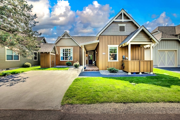 A two-story house with a covered front porch, a garage, and a well-maintained lawn.